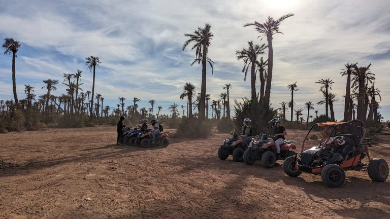 Un rider en quad sur une piste poussiéreuse avec les montagnes de l'Atlas en arrière-plan.