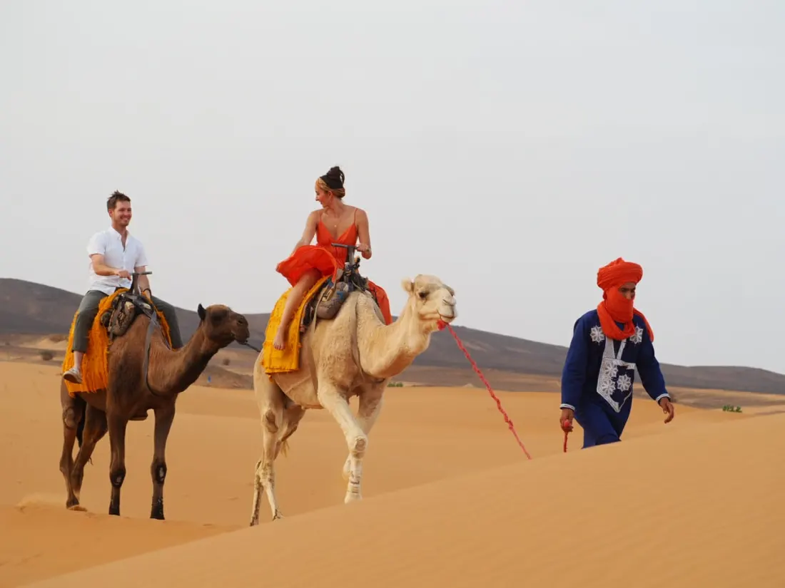Viaggiatori in sella ai dromedari con una guida berbera – Tour nel Deserto di 3 Giorni da Ouarzazate a Marrakech