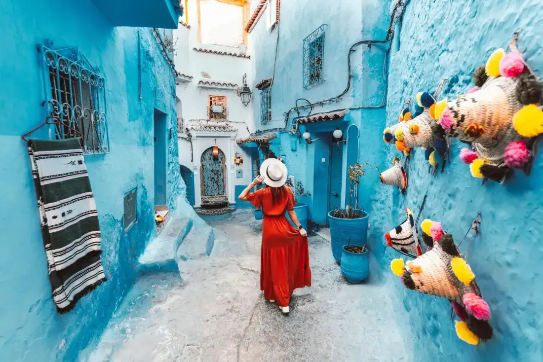 Donna in rosso in una strada blu di Chefchaouen – Tour del Marocco di 6 Giorni da Tangeri